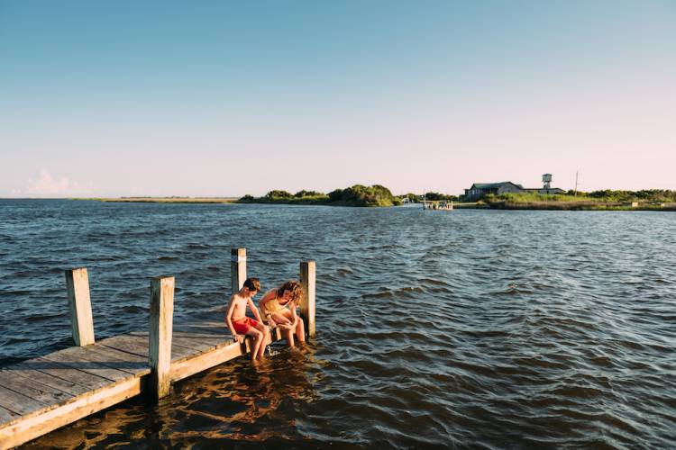 siblings on a pier dangling feet in the water in the Outer Banks